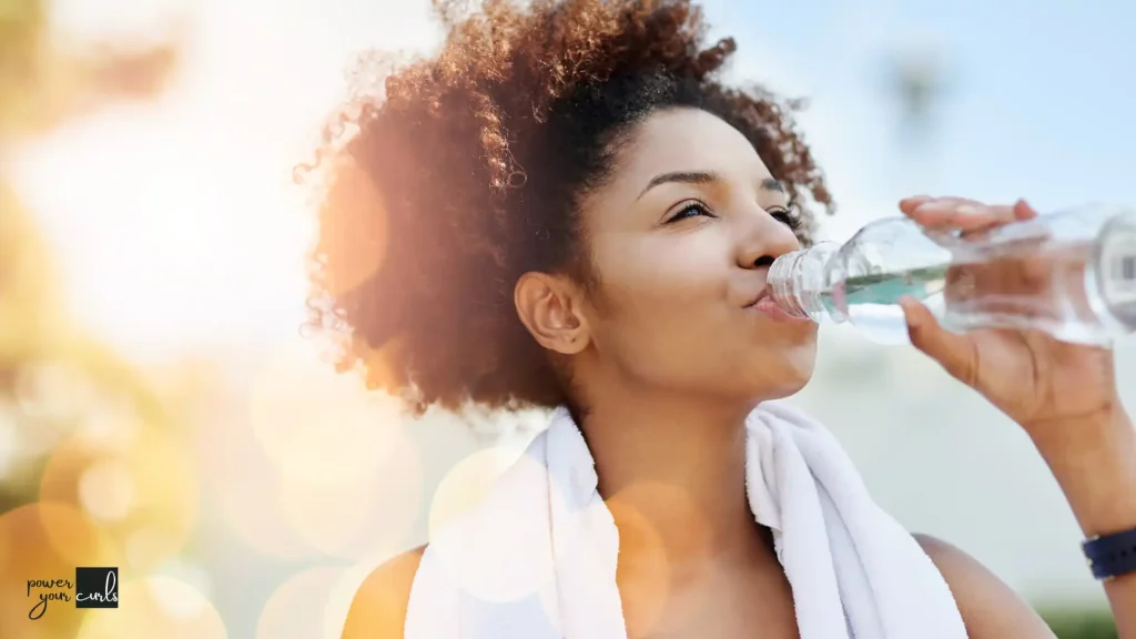 Curly haired woman drinking water